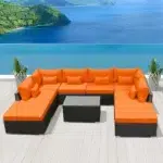 Outdoor 8-seater black rattan sectional sofa with bright orange cushions on a patio