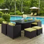 7-piece dark brown wicker outdoor dining set with green cushions, including ottoman and table without glass top