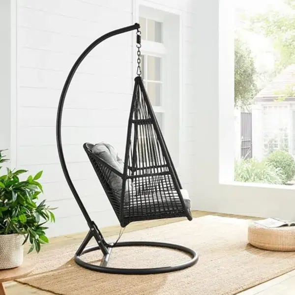 Single-seater hanging swing with a black braided rope and metal stand, placed in a garden setting.