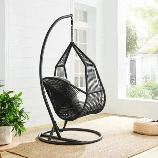 Single-seater hanging swing with a black braided rope and metal stand, placed in a garden setting.