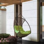 Dark brown single seater hanging swing without stand, placed in a garden setting.