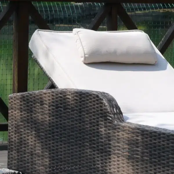 Rattan wicker long reclining outdoor chaise lounge in brown and off-white with cushions.