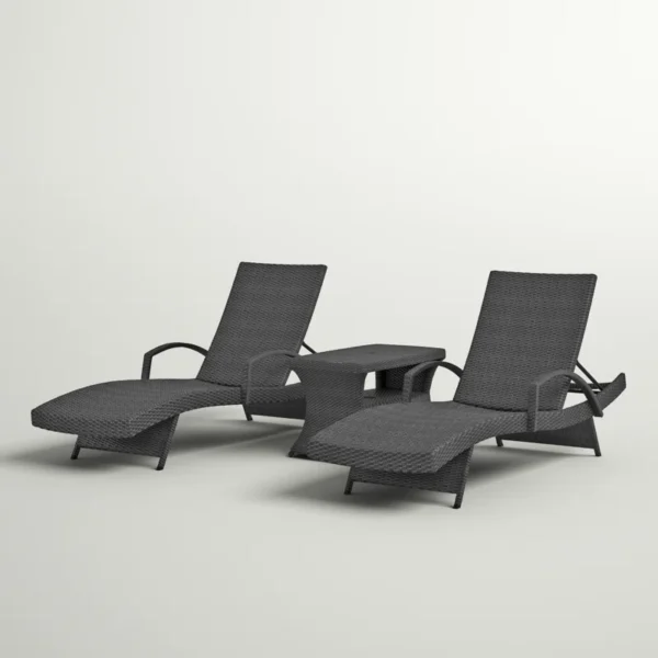 Black outdoor chaise lounge set with matching side table on a patio with greenery in the background.