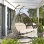 Double seater hanging swing chair with dark brown wicker frame and cream cushions