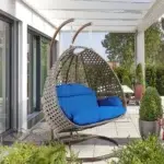 Double seater hanging swing chair in dark brown and blue, made of sturdy rattan with soft cushions, perfect for outdoor relaxation.