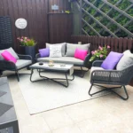 Grey 4-seater outdoor sofa set with plush cushions and matching table on a patio.
