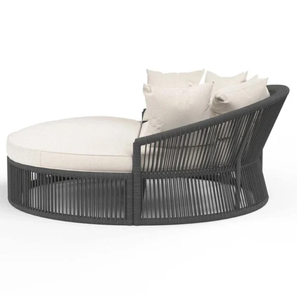 Round black daybed with cushions and low-profile table, styled for outdoor relaxation