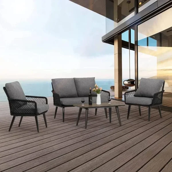 4-seater outdoor/indoor black and grey sofa set with center table and cushioned chairs, placed on a patio.