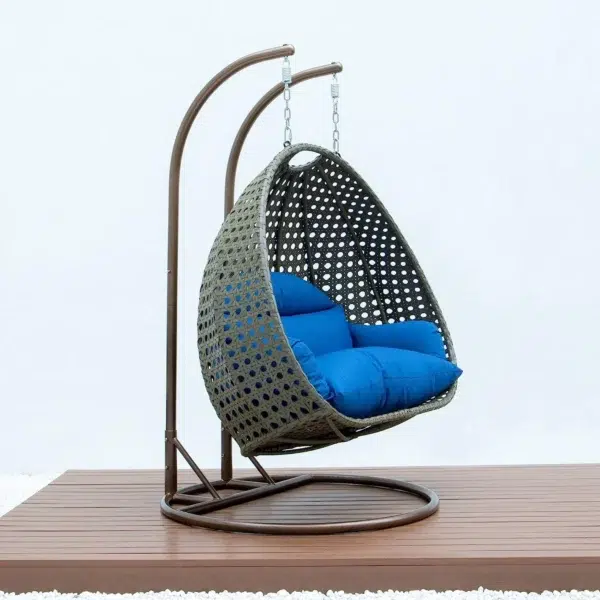 Double seater hanging swing chair in dark brown and blue, made of sturdy rattan with soft cushions, perfect for outdoor relaxation.