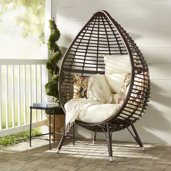 Brown single seater swing basket hanging in balcony with cushions.