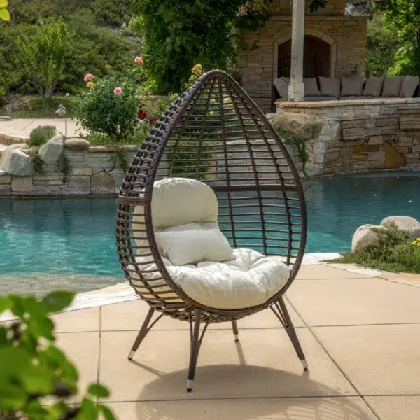 Brown single seater swing basket hanging in balcony with cushions.