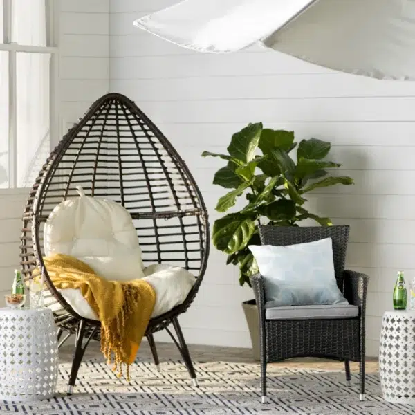 Brown single seater swing basket hanging in balcony with cushions.