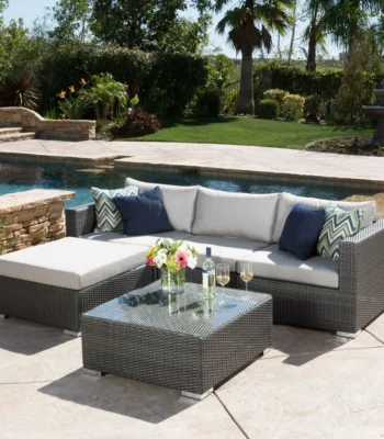 4 seater outdoor wicker sectional sofa set in brown frame with light grey cushions placed on a patio.