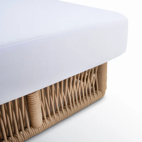 Beige rope sun lounger with a plush white cushion placed outdoors for comfortable lounging.