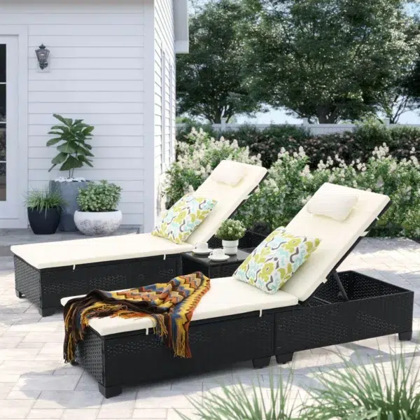 Set of 2 off-white wicker rattan outdoor chaise lounge chairs with matching side table on a patio.