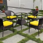 Outdoor and indoor patio set with rattan bistro chairs and a small round table on a terrace.