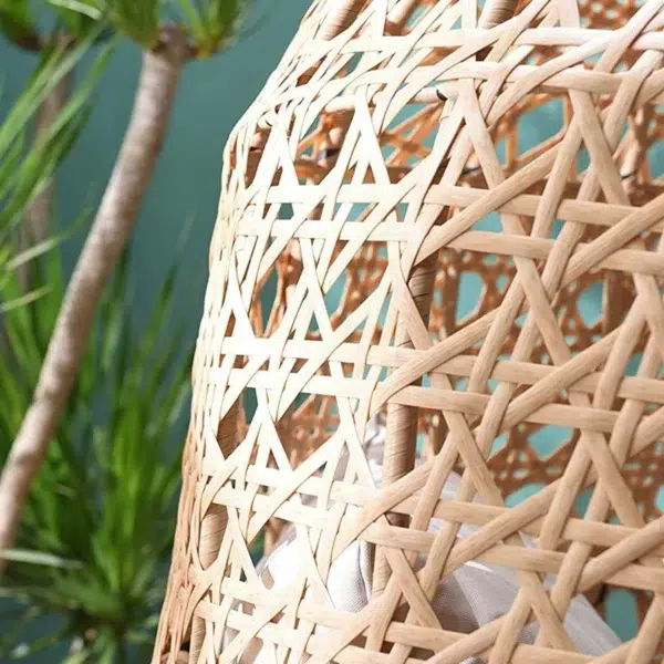 Beige rattan wicker cocoon chair with a comfortable cushion for outdoor patio or garden