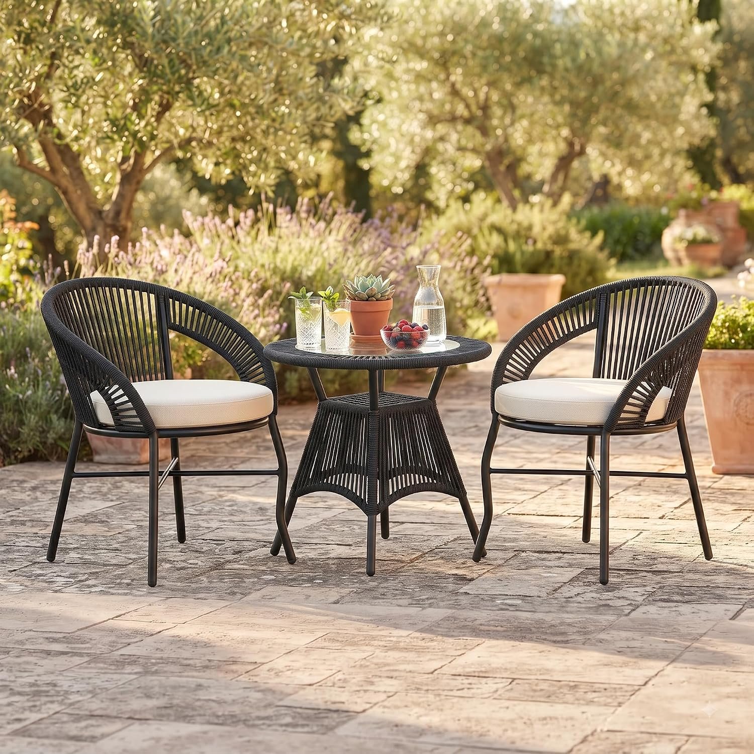 Loccus 3-Piece Outdoor Rope Patio Furniture Set with 2 Chairs & Round Table, Cream Cushions, Handwoven Design for Balcony, Garden, Terrace & Backyard 3-piece outdoor rope patio furniture set with two black handwoven rope chairs, cream cushions, and a round matching table in a garden patio setting.