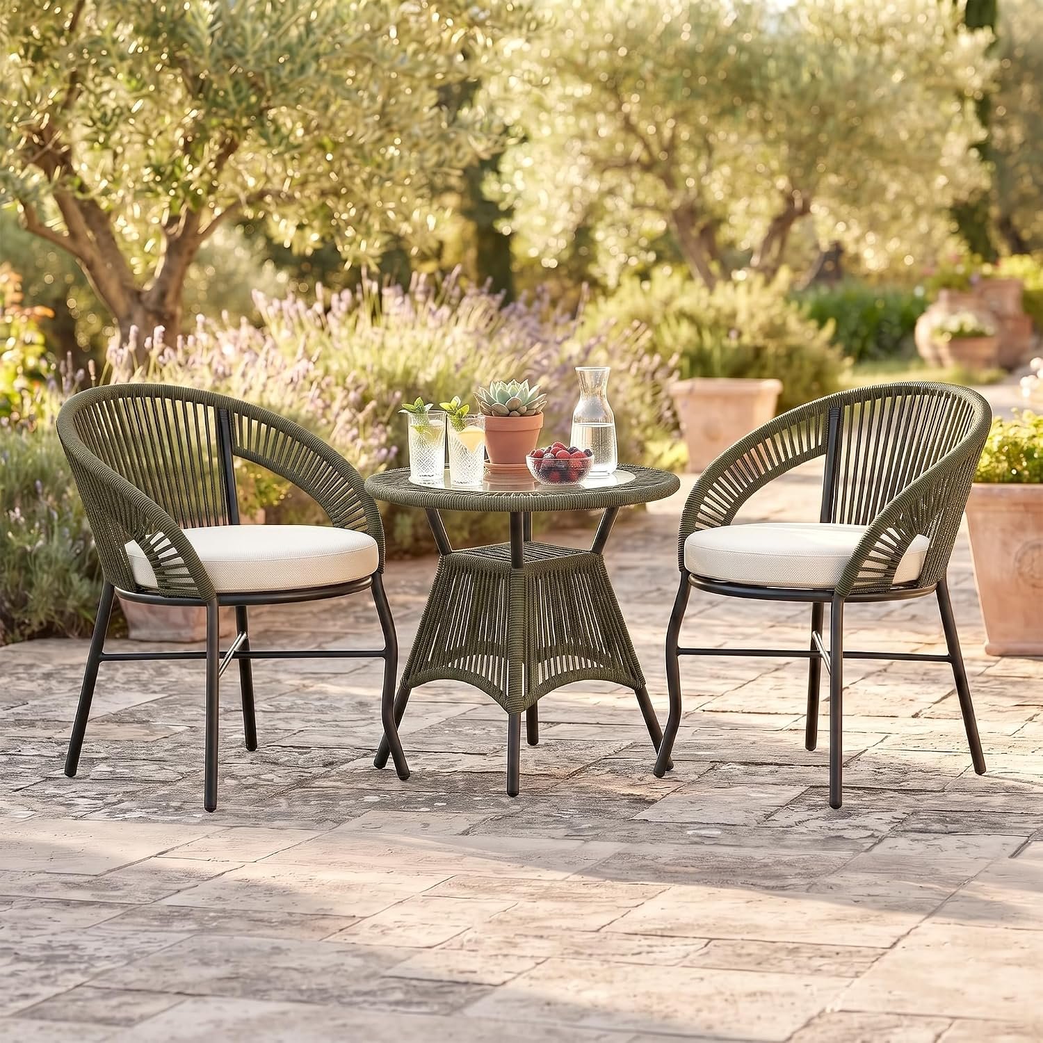 Loccus 2 Seater Outdoor Patio Furniture Set with two handwoven rope chairs, cream cushions and round glass-top table in a garden setting.