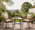Modern wicker bistro set with two cushioned chairs and round glass-top table in a beautiful garden patio